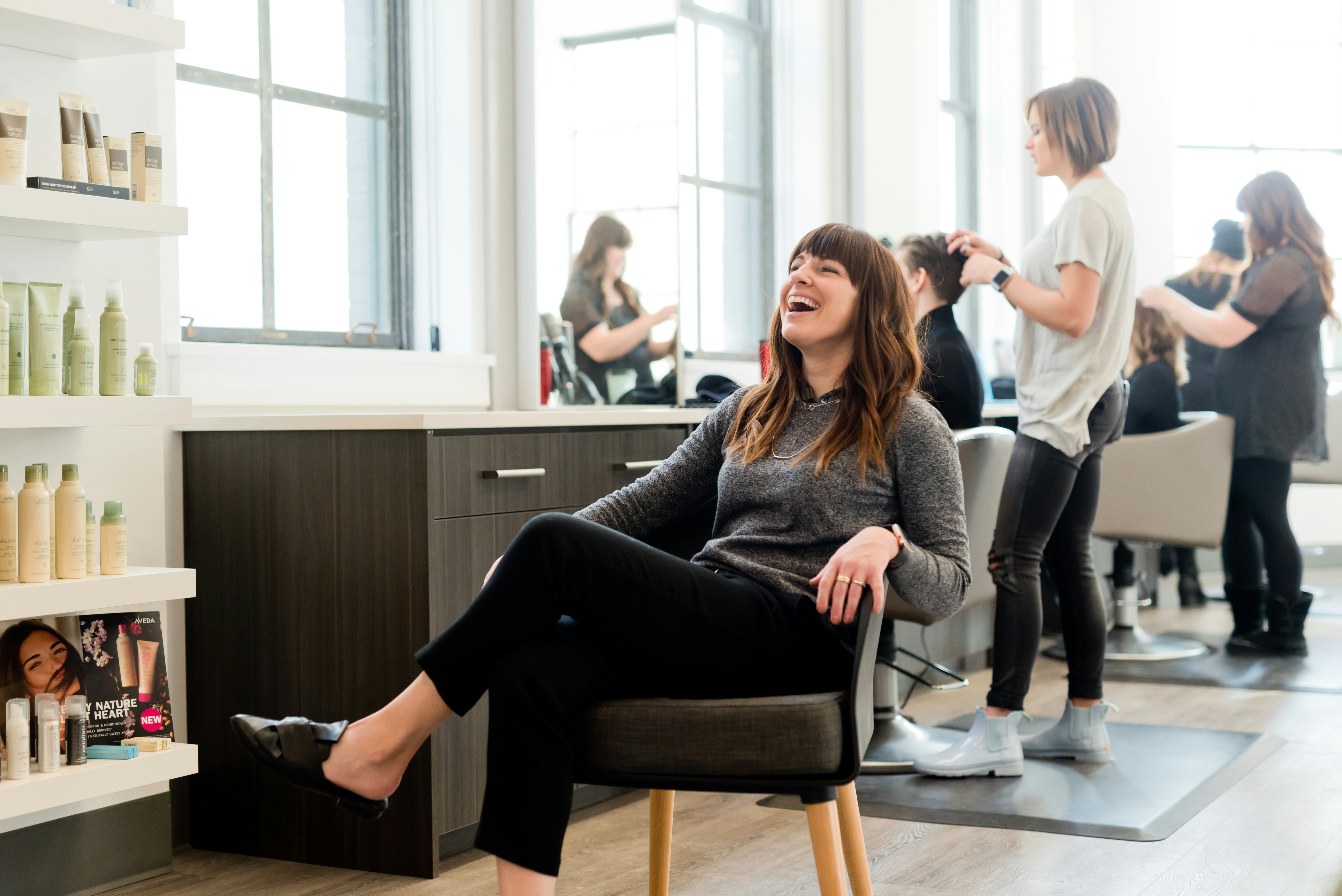 A stylist braiding hair in soft light